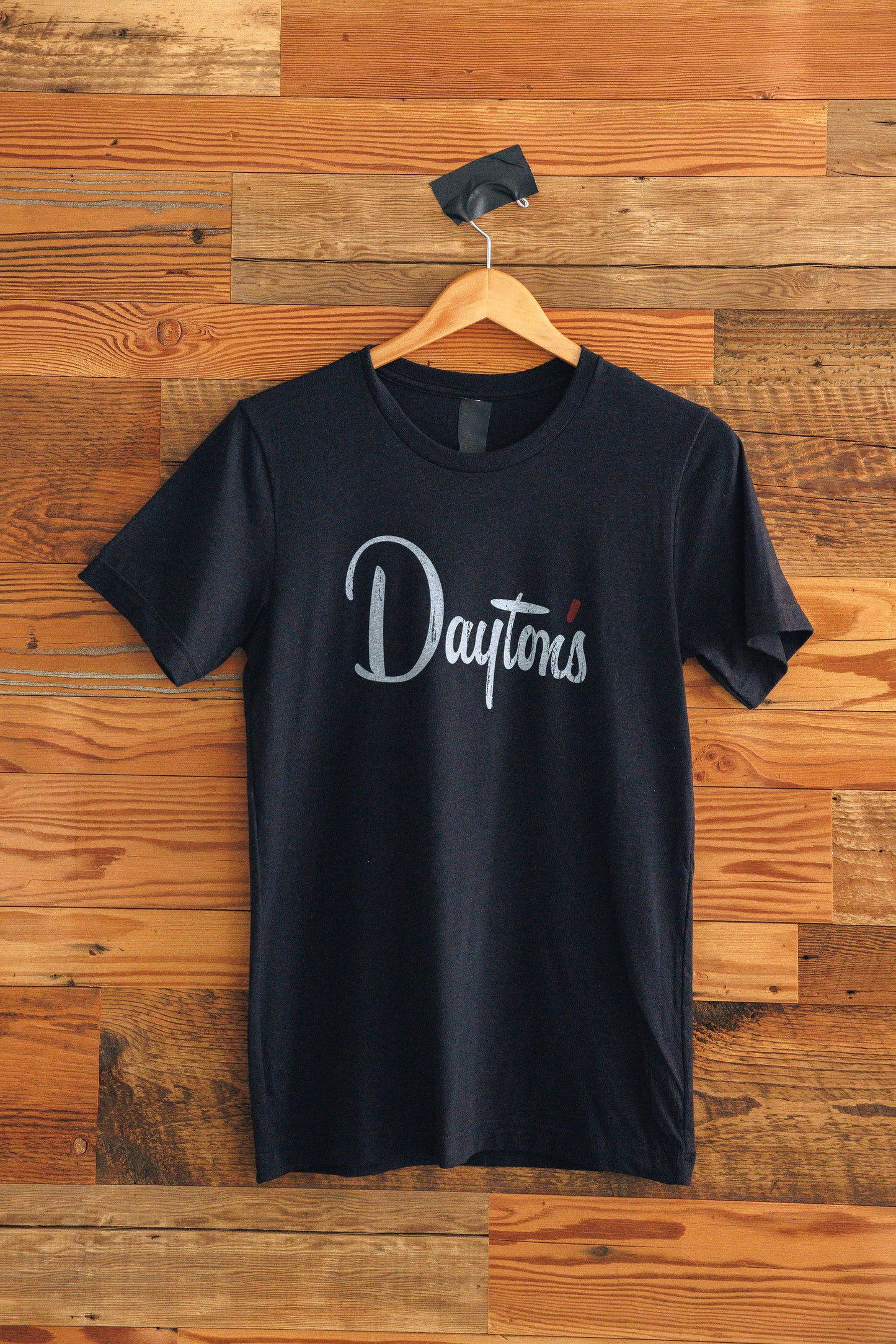 Black t-shirt with 'Dayton' logo on a wooden background
