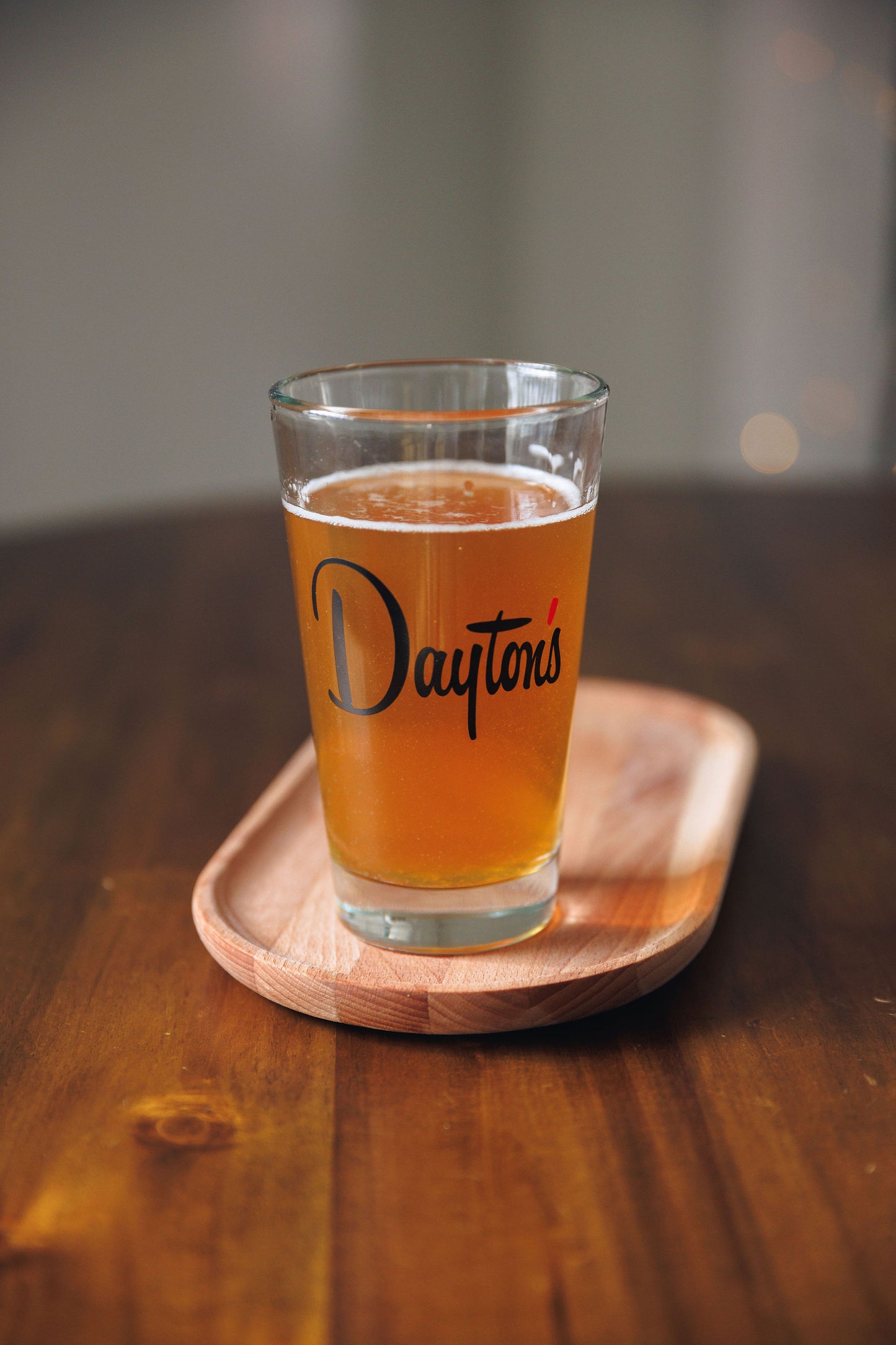 Glass of beer with 'Dayton's' branding on a wooden coaster