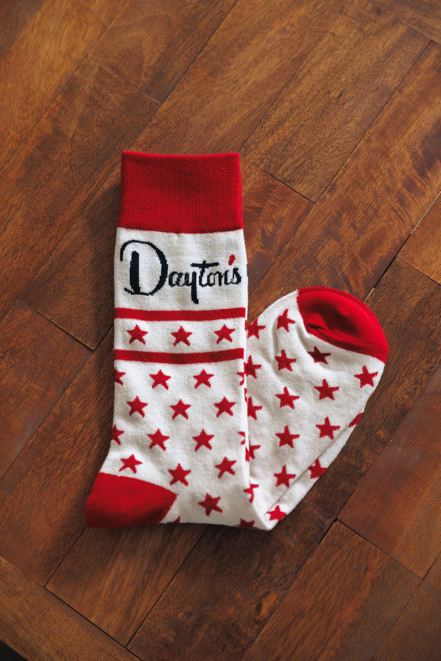 White socks with red stars and red cuffs on a wooden floor, featuring the word 'Dayton'.