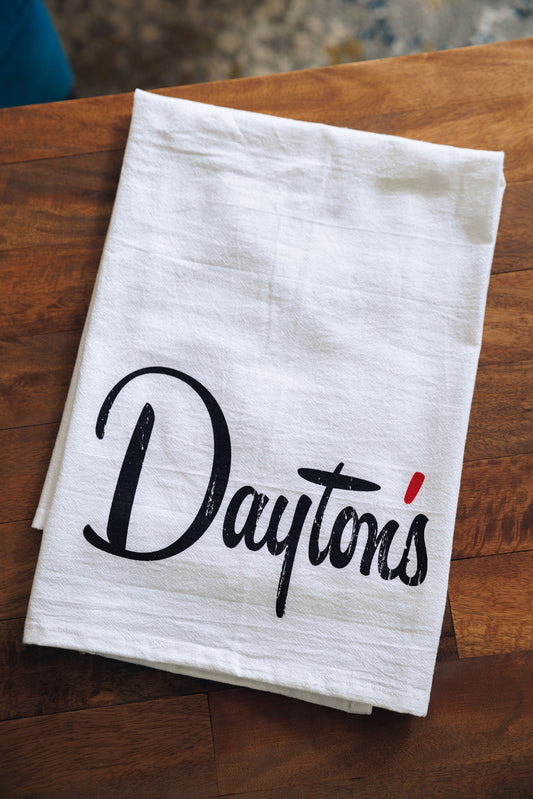 White towel with 'Dayton's' printed on it, placed on a wooden surface.