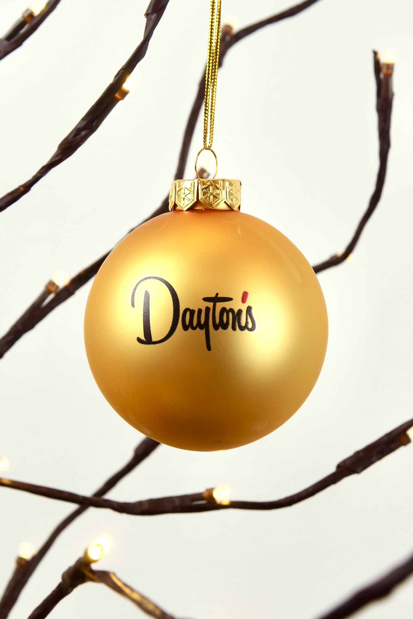Gold ornament with 'Dayton's' text hanging on a branch