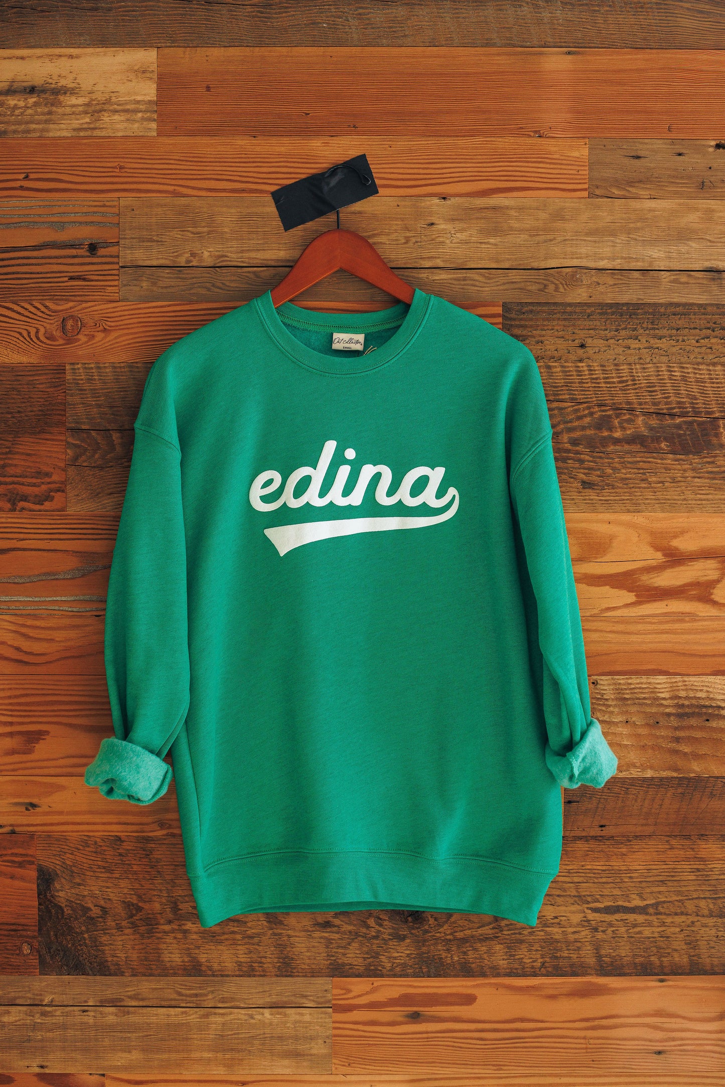 Green sweatshirt with 'edina' print on a wooden background