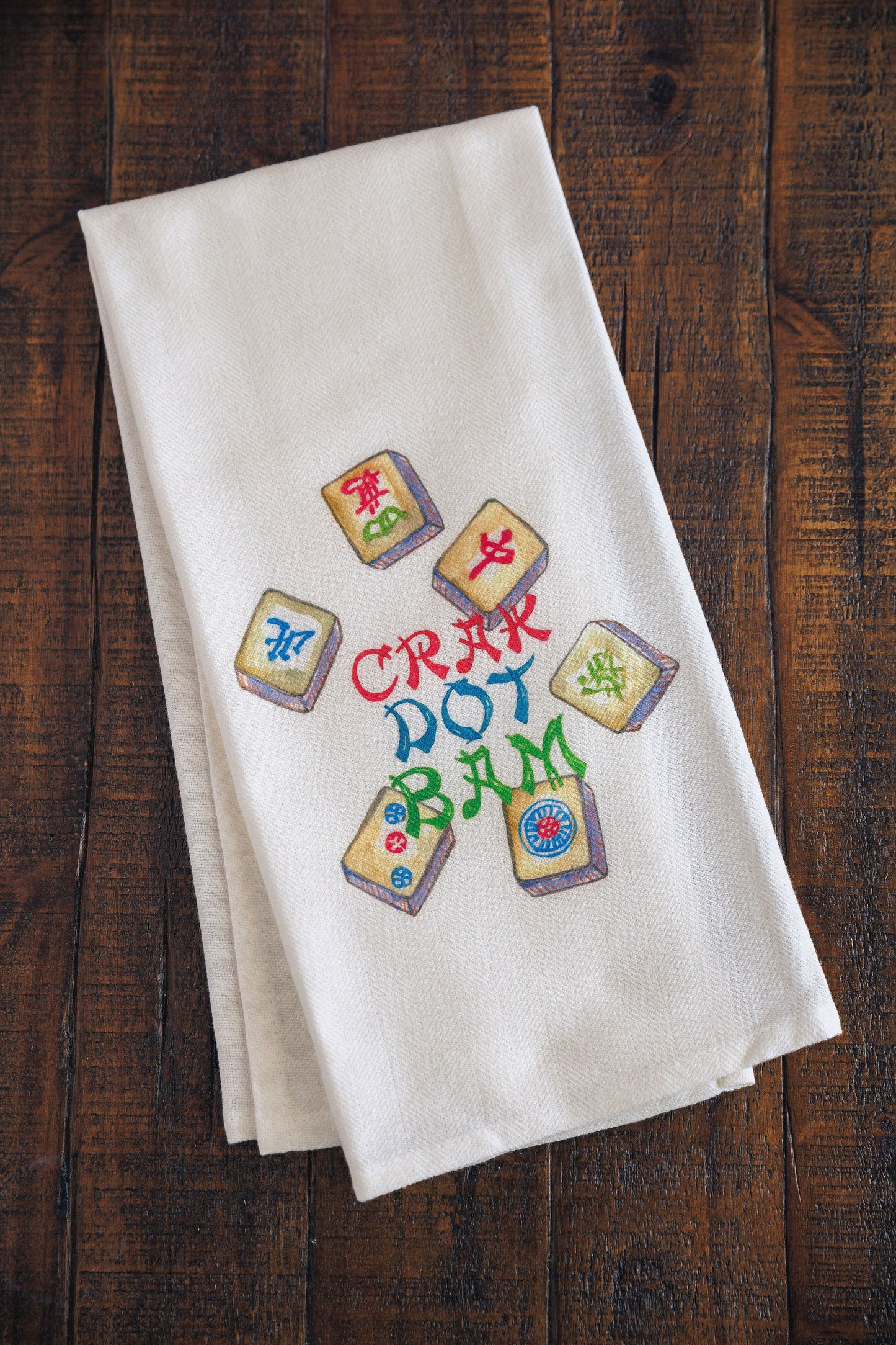 White towel with colorful text and mahjong symbols on a wooden surface