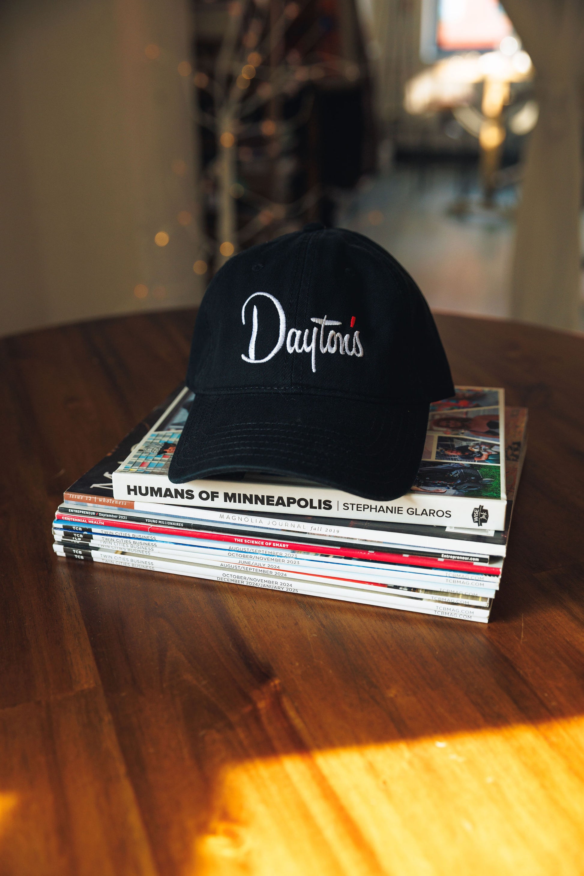 Black cap with 'Dayton's' logo on a stack of books on a wooden table
