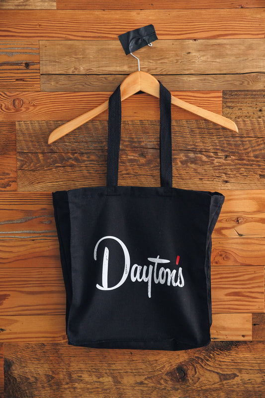 Black tote bag with 'Daytons' text on a wooden background