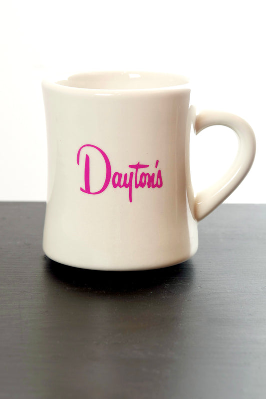 White mug with 'Dayton's' logo on a black surface
