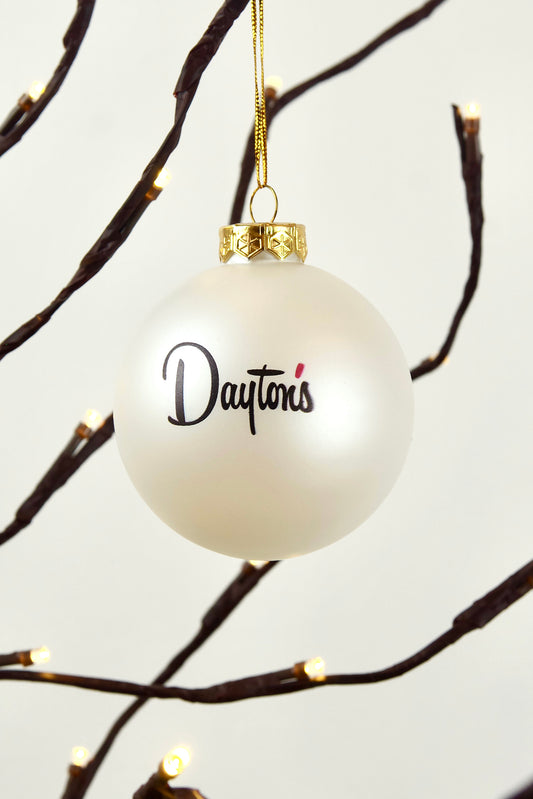 White ornament with 'Dayton's' text hanging on a branch with lights