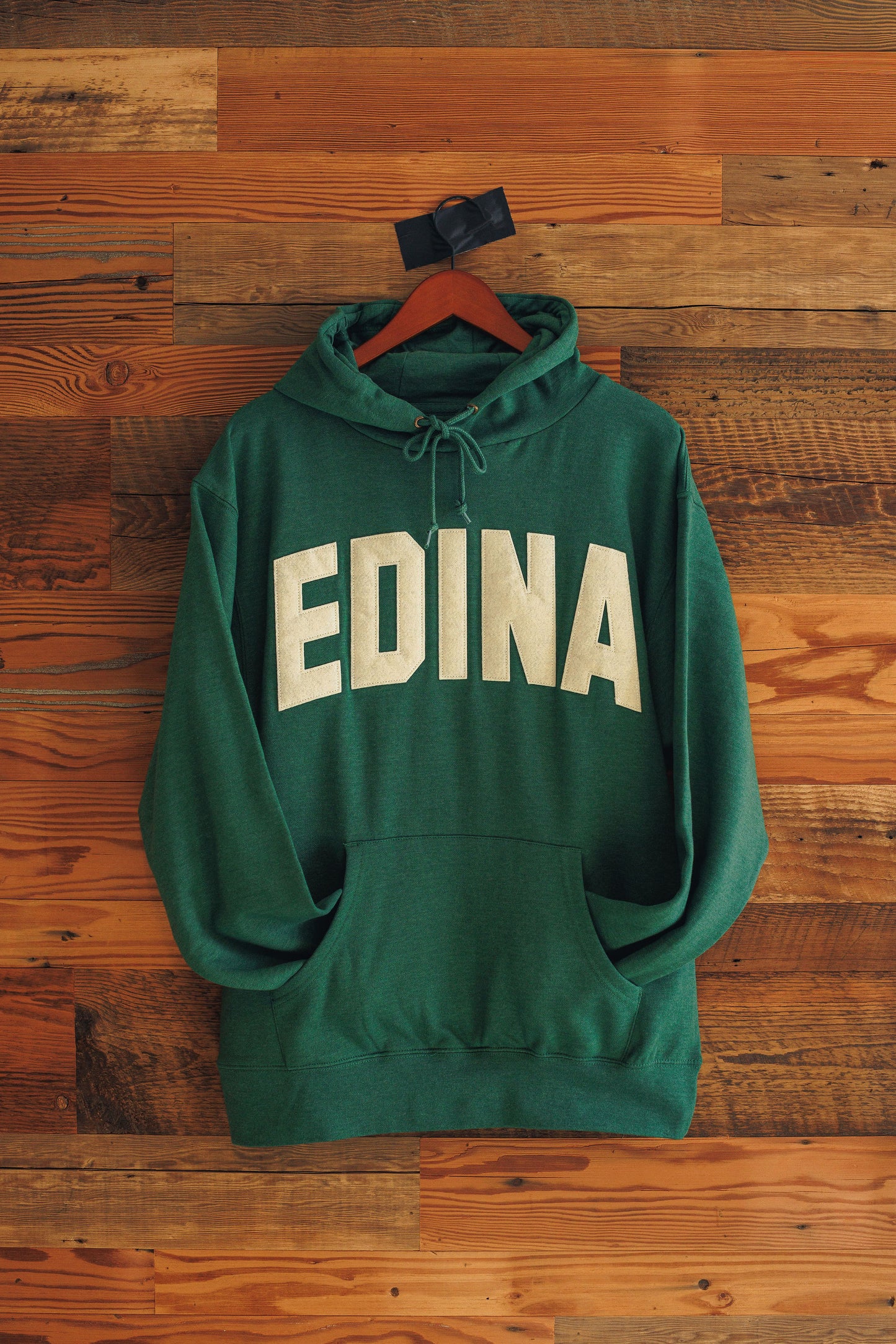 Green hoodie with 'EDINA' text on a wooden background