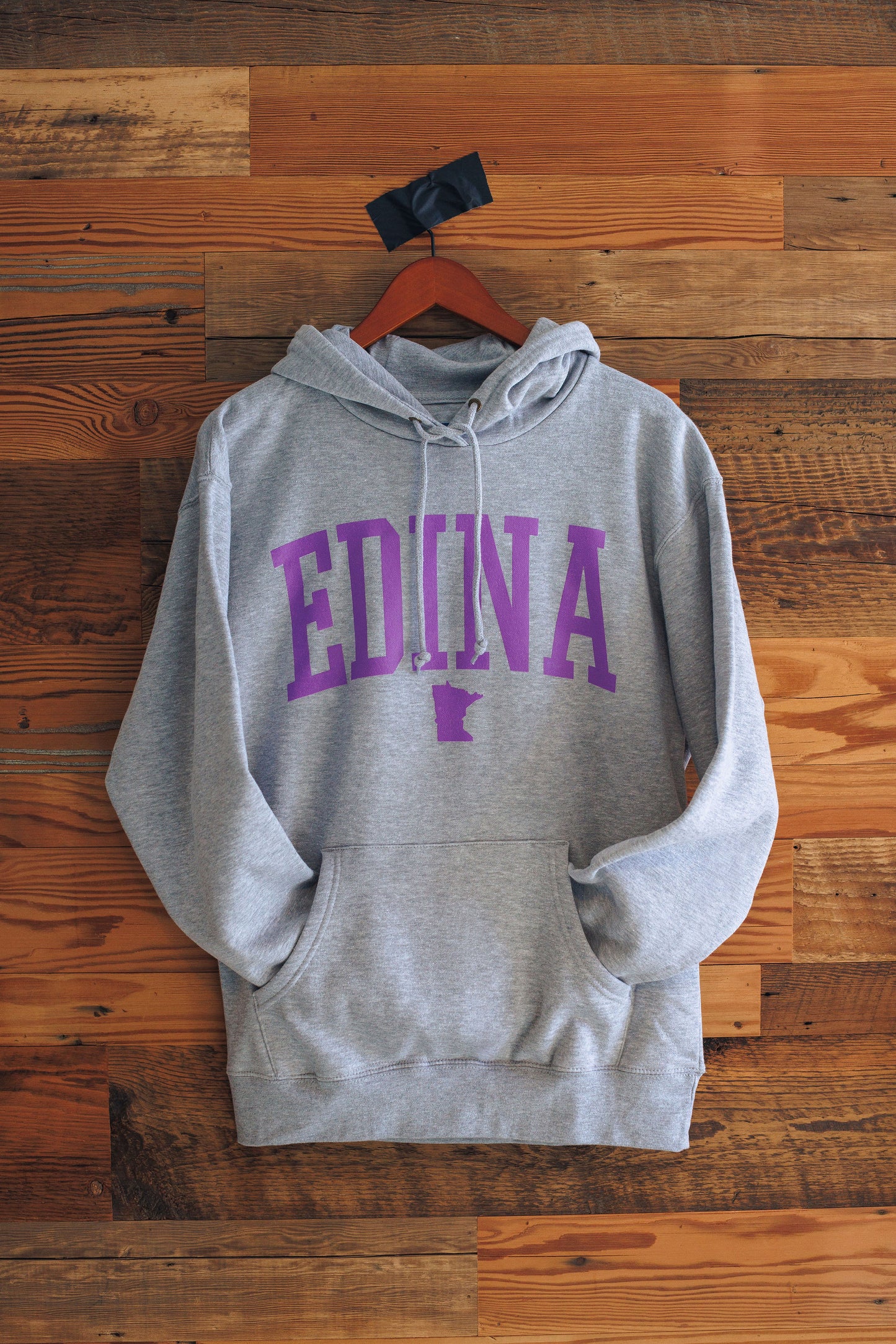 Gray hoodie with 'Edina, MN' printed in purple on a wooden background