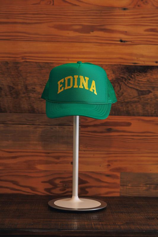 Green cap with 'EDINA' text on a stand against a wooden background