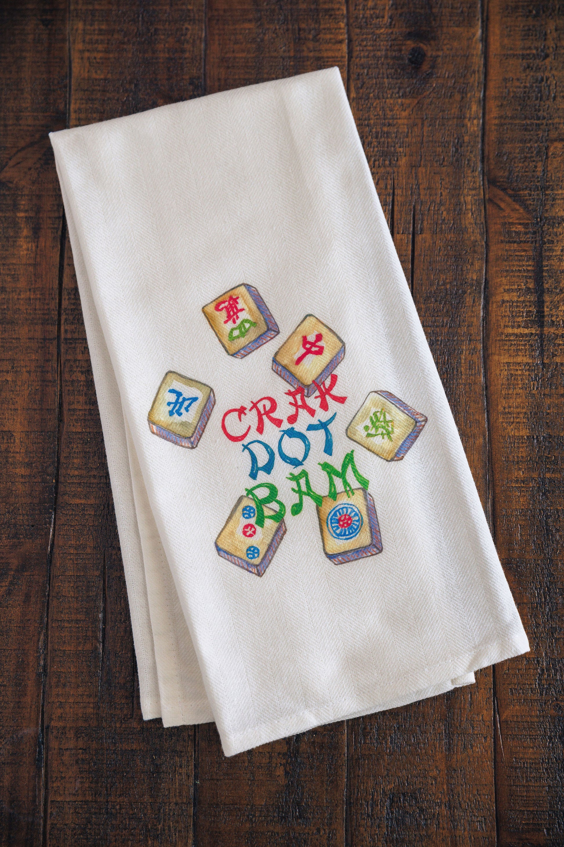 White towel with colorful text and mahjong symbols on a wooden surface