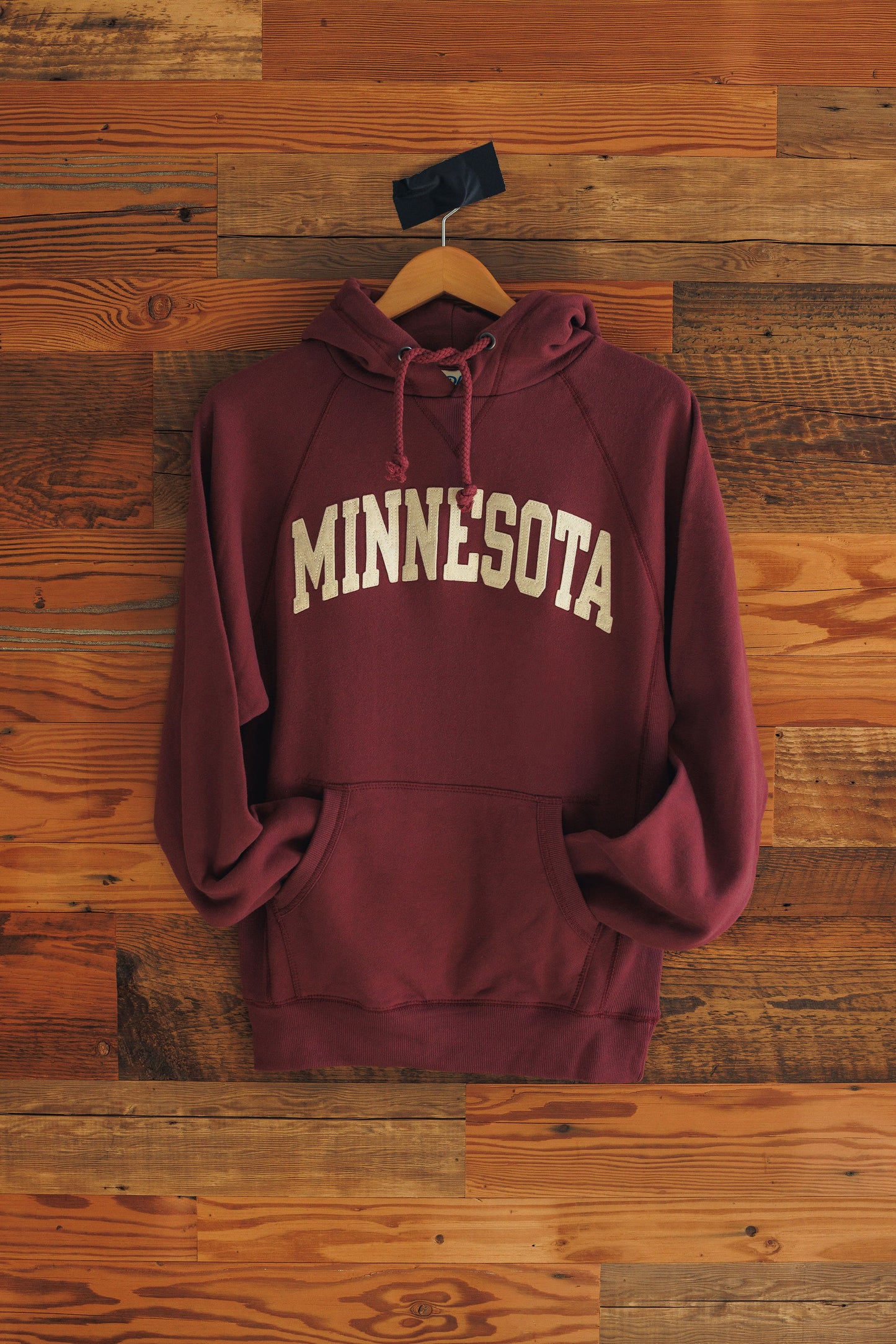 Maroon hoodie with 'MINNESOTA' text on a wooden background