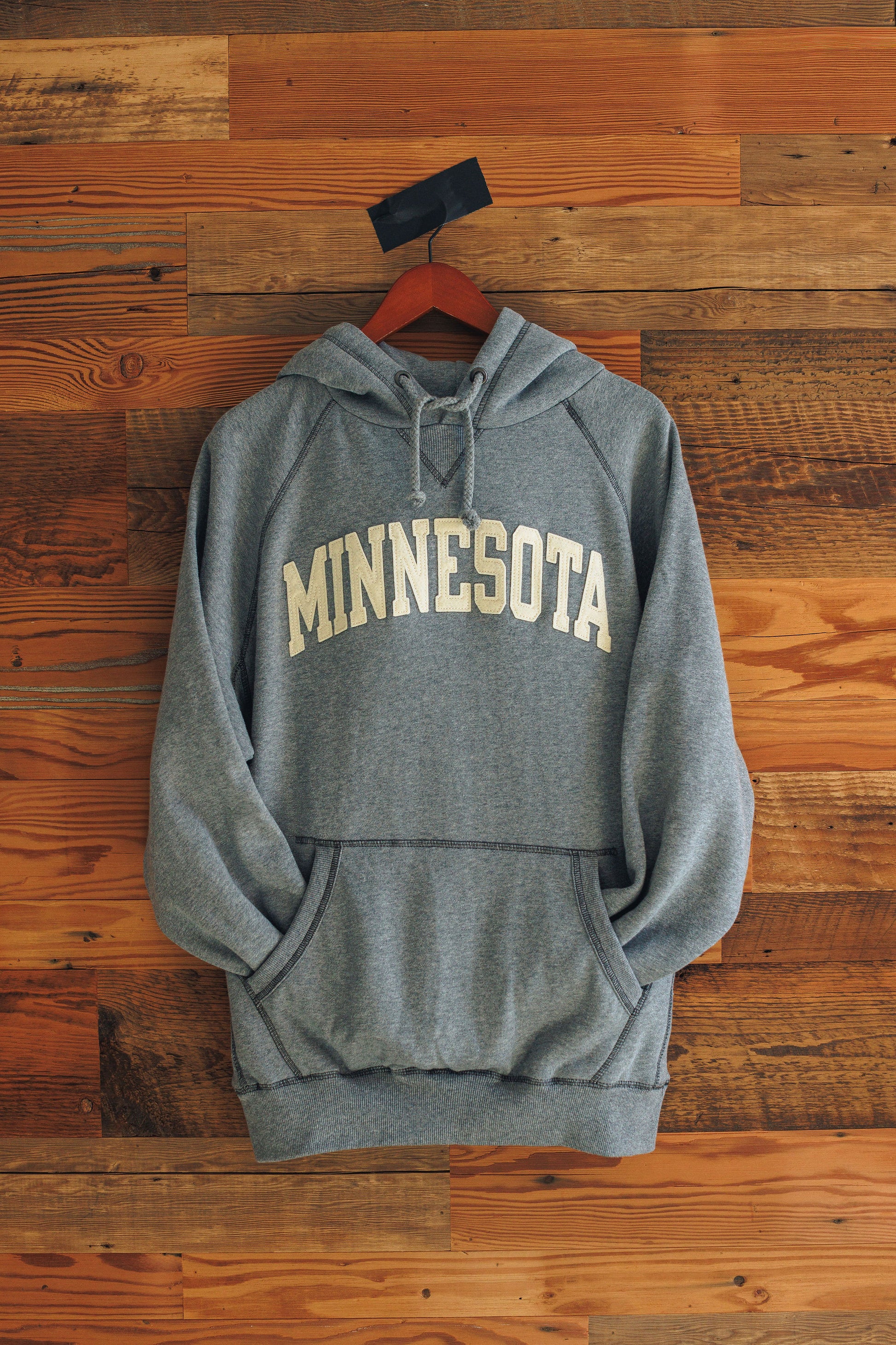 Gray hoodie with 'MINNESOTA' text on a wooden background