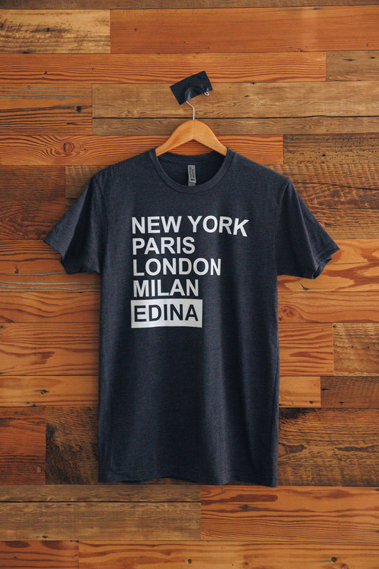 Black t-shirt with 'New York Paris London Milan Edina' text on a wooden background