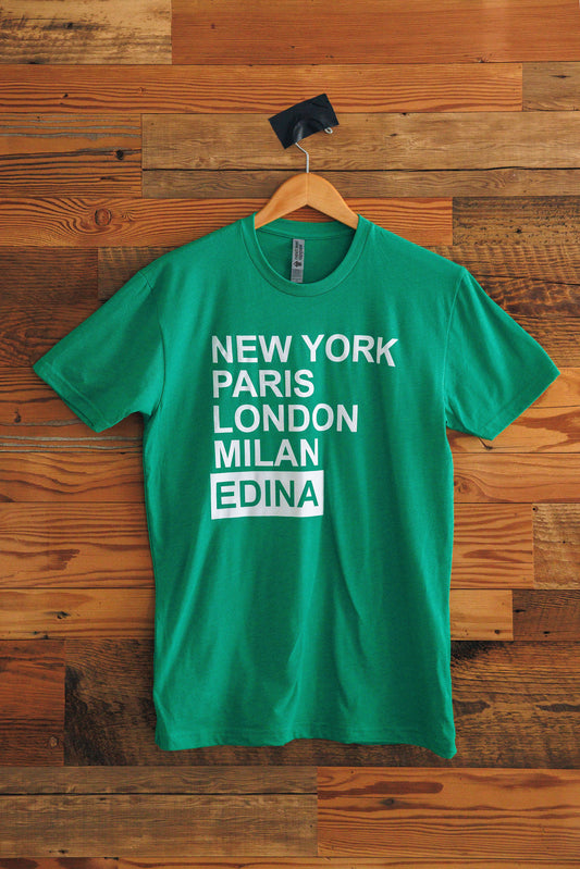 Green t-shirt with 'New York Paris London Milan Edina' text on a wooden background