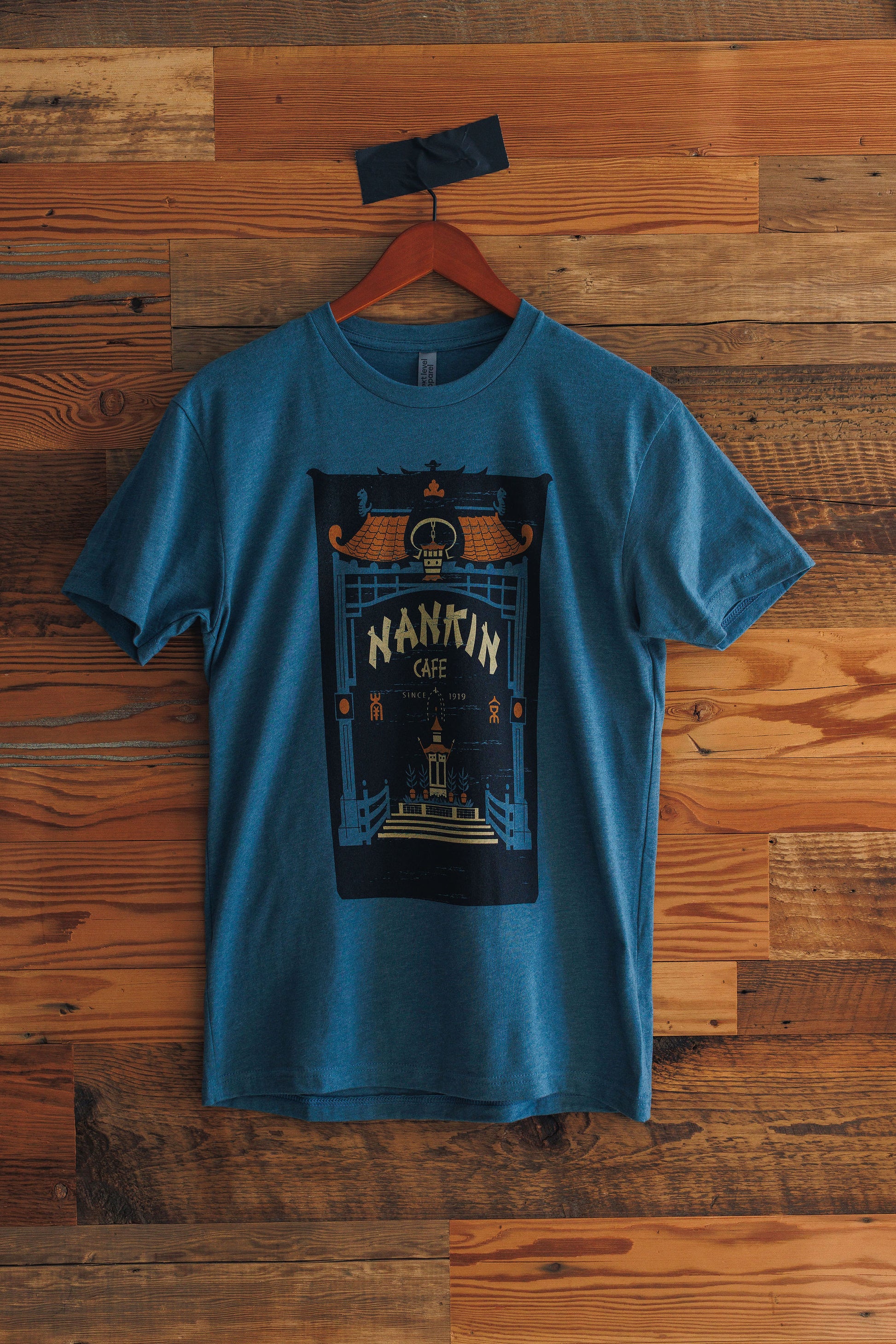 Blue t-shirt with graphic design on a wooden wall