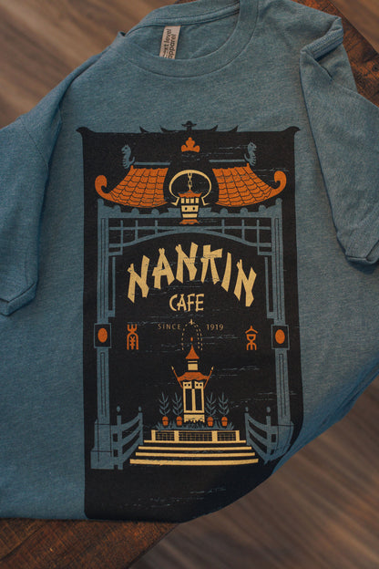 Blue sweatshirt with 'Nankin Cafe' graphic design on a wooden surface