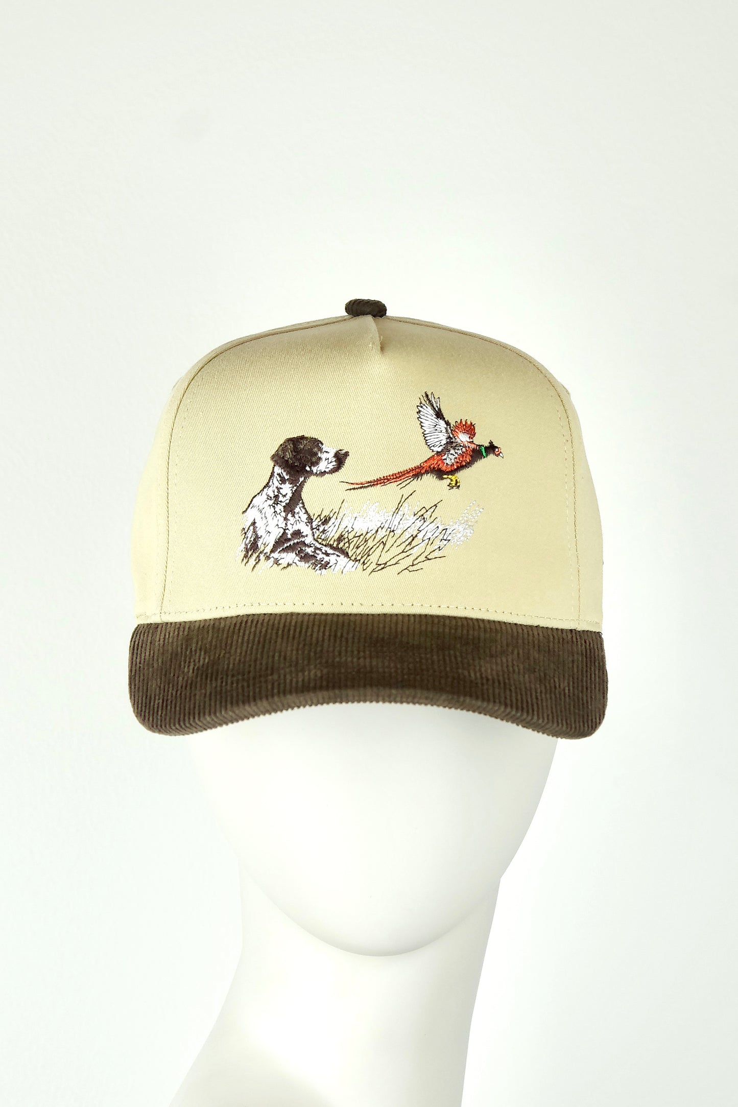 Cap with a dog and pheasant design on a mannequin head against a white background
