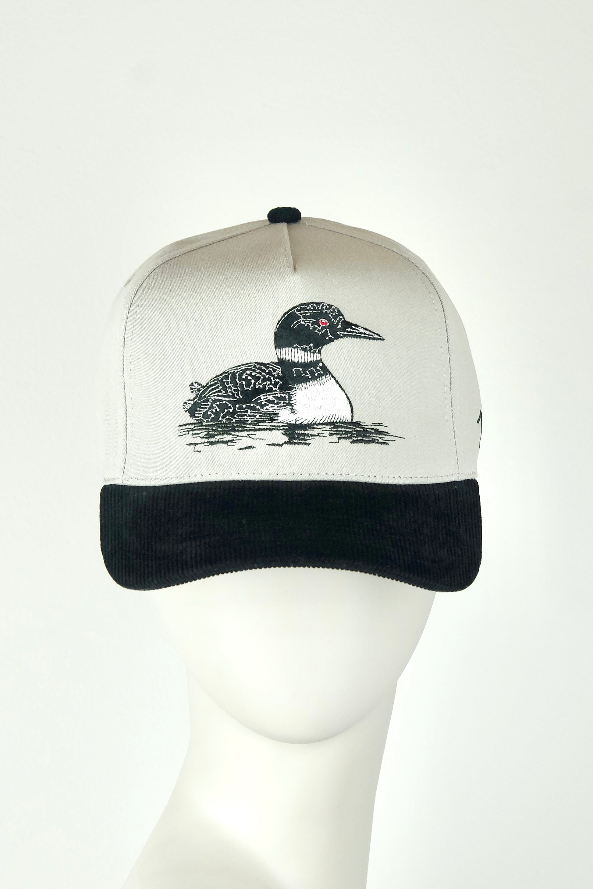 Cap with a loon design on a mannequin head against a white background